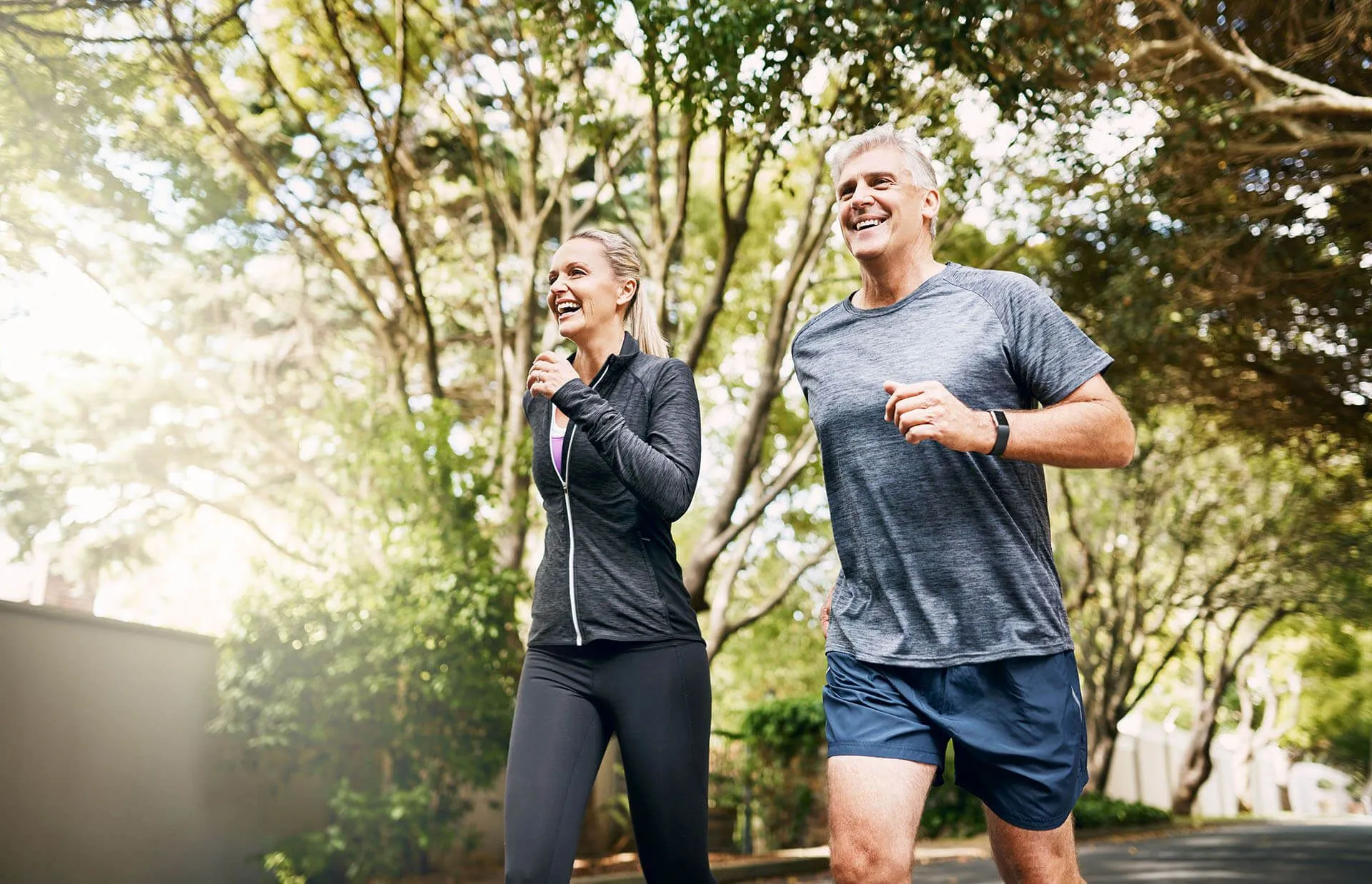 A 50+ man and a woman are jogging on a street.