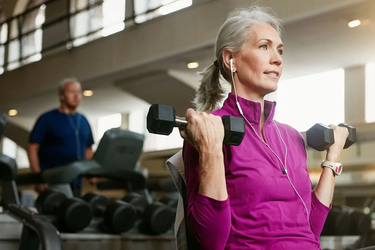 Over 50 woman lifting dumbbells in a gym